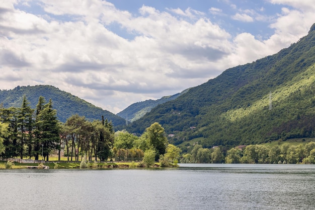 Gentle slope of high mountain framed Lago d'Idro with evergreen trees, Brescia, Lombardy, Italy