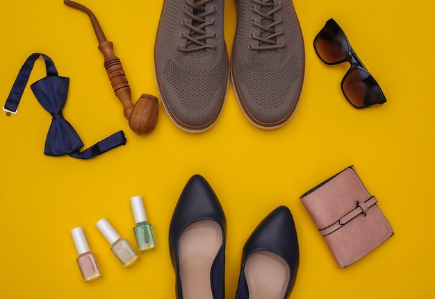 Gentlemen and lady shoes and accessories on yellow background. Top view