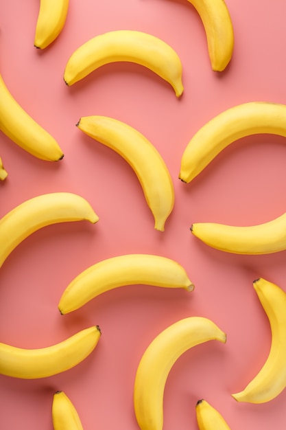 Geometric pattern of bananas on a pink background. The view from the top. Minimal flat style. Pop art design, creative summer concept.