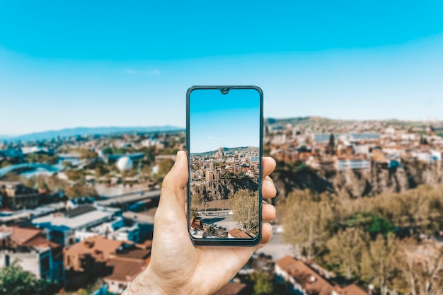 Georgia and tbilisi landscape a hand with a smartphone photographing the sights of georgia and tbilisi