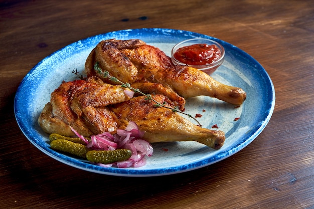 Georgian cuisine dish chicken tapaka or tabaka on a plate, on wooden surface