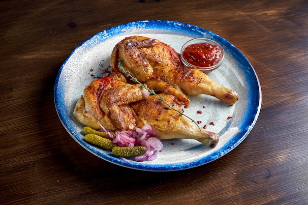 Georgian cuisine dish chicken tapaka or tabaka on a plate, on wooden surface