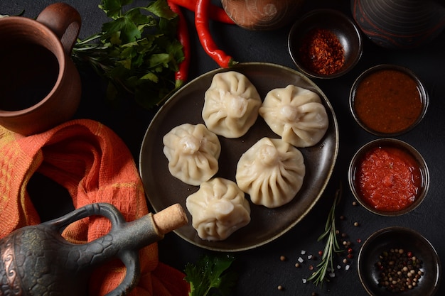 Georgian dumplings Khinkali with meat and red pepper, Traditional National Georgian cuisine. Khinkali with   local sauces - tkemali, satsebeli, adzhika.