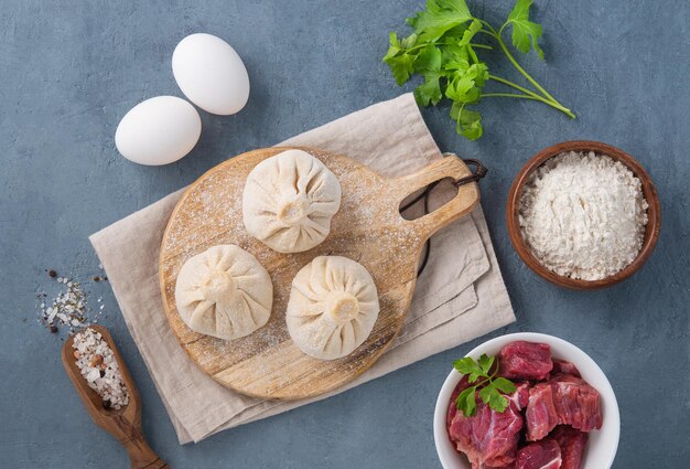 Georgian Khinkali dumplings with meat herbs and spices on a wooden board not cooked on a blue background