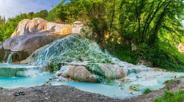 Geothermal pool and hot spring in Tuscany, Italy. Bagni San Filippo natural thermal waterfall in the morning with no people. The White Whale amidst forest.