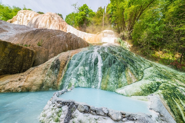 Geothermal pool and hot spring in Tuscany, Italy. Bagni San Filippo natural thermal waterfall in the morning with no people. The White Whale amidst forest.