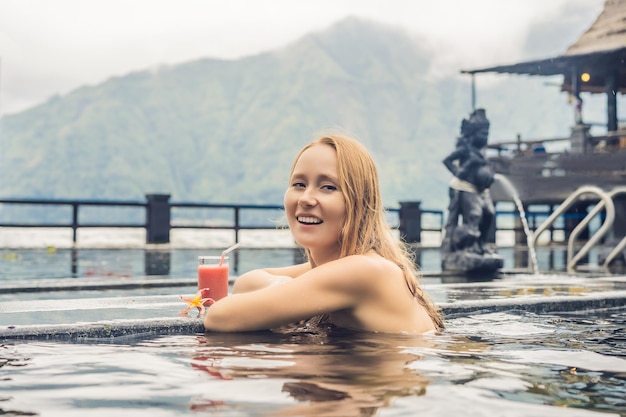 Geothermal spa woman relaxing in hot spring pool against the lake hot springs concept drinking guava