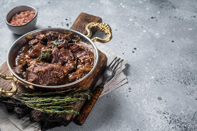 German braised beef cheeks in brown red wine sauce Gray background Top view Copy space