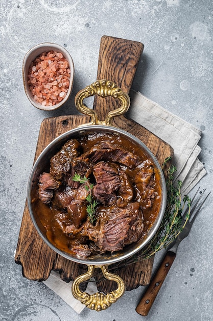 German braised beef cheeks in brown red wine sauce Gray background Top view