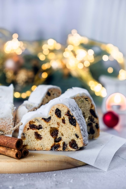 German Stollen cake traditional European dessert with dried fruit raisins nuts and marzipan Christmas pie with cinnamon and Christmas lights on background Recipe of homemade dessert for holidays