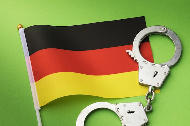 Germany flag and handcuffs on a green background, the concept of crimes in the country