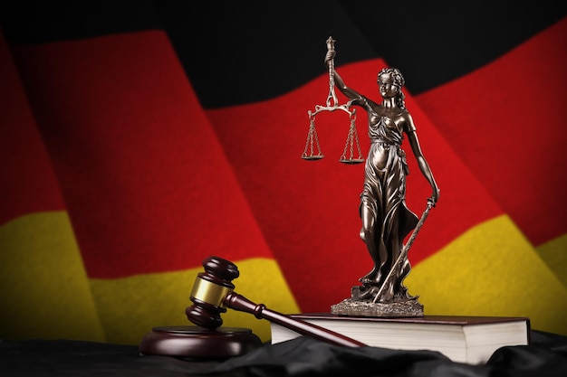 Germany flag with statue of lady justice constitution and judge hammer on black drapery Concept of judgement and guilt