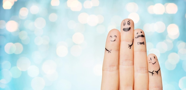 gesture, family, people and body parts concept - close up of two hands showing fingers with smiley faces over blue holidays lights background