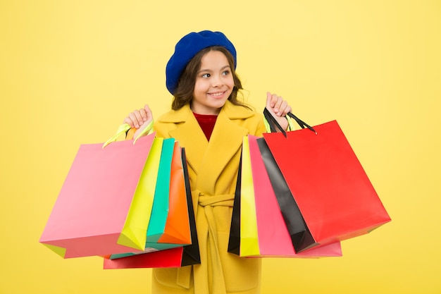 Get discount shopping on birthday or holiday Fashionista adore shopping Obsessed with shopping Girl cute kid hold shopping bags on yellow background Mid season sale Shop with discount card