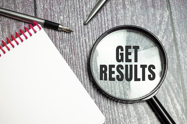 Get results symbol on magnifier and pen on wooden background