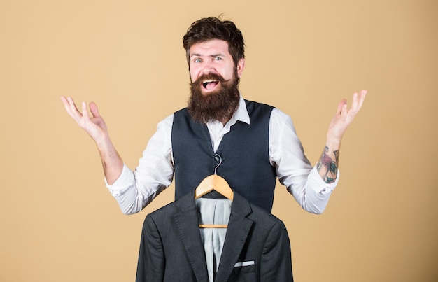 Getting excited about fashion Emotional look of bearded fashion model Fashion designer helping to choose suit jacket Fashion stylist holding readymade formal coat