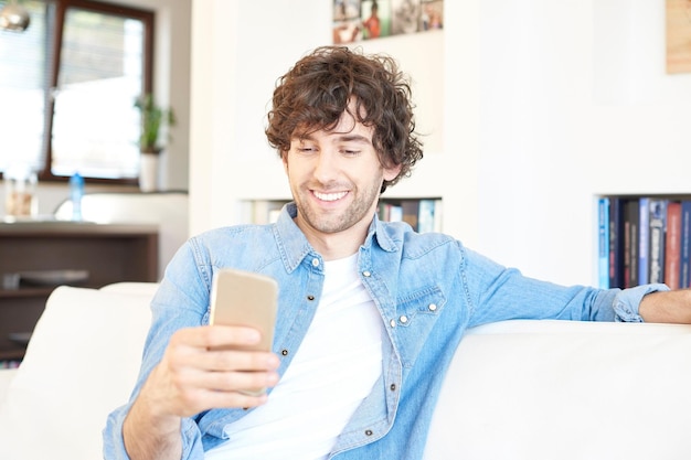 Getting good news Shot of a happy young man text message while relaxing at home