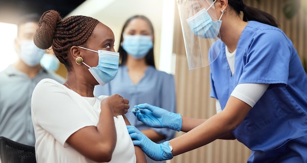 Getting her booster shot Cropped shot of an attractive young businesswoman getting her covid vaccination from a female nurse in the office