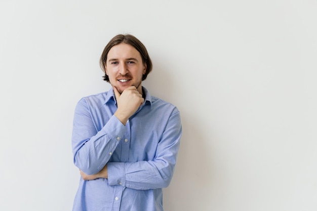 Getting idea Smiling thoughtful handsome man standing on white isolated background and touching his chin with hand