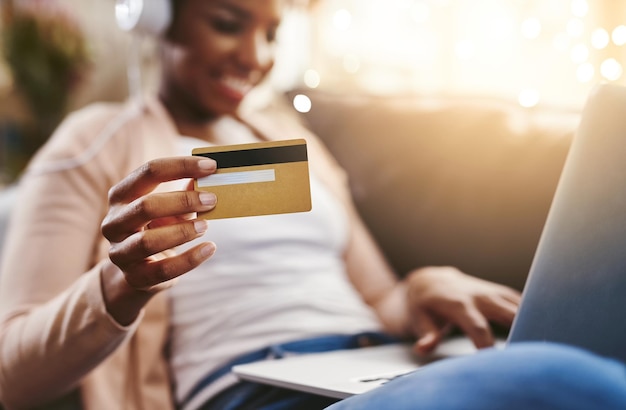 Getting new music has never been easier Shot of an unrecognizable young woman shopping online while chilling at home on the sofa