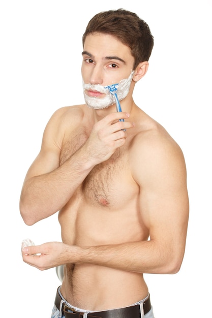 Getting ready for the day. Portrait of a muscular shirtless handsome young man shaving his face isolated on white