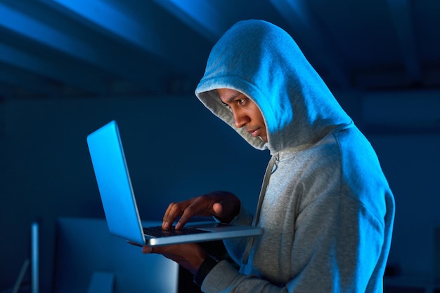 Getting ready to share your personal information with the world Shot of a young male hacker using a laptop in the dark