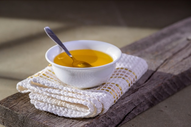 Ghee butter from India in white dinnerware container on wooden table.