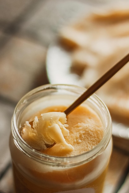 Ghee butter in glass jar and sliced bread on table. Healthy eating, breakfast