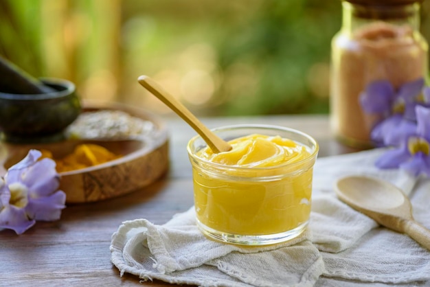 Ghee butter in glass jar with wooden spoon on wooden table with blurred background