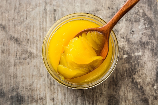 Ghee or clarified butter in jar and wooden spoon on wooden table top view