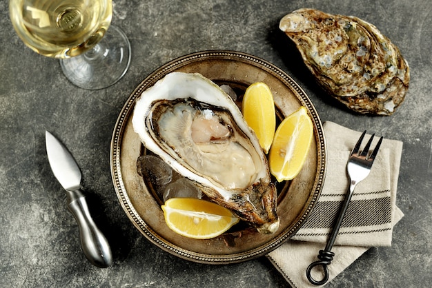 Giant fresh uncooked oysters in a shell with lemon on ice. Healthly food. Top view.