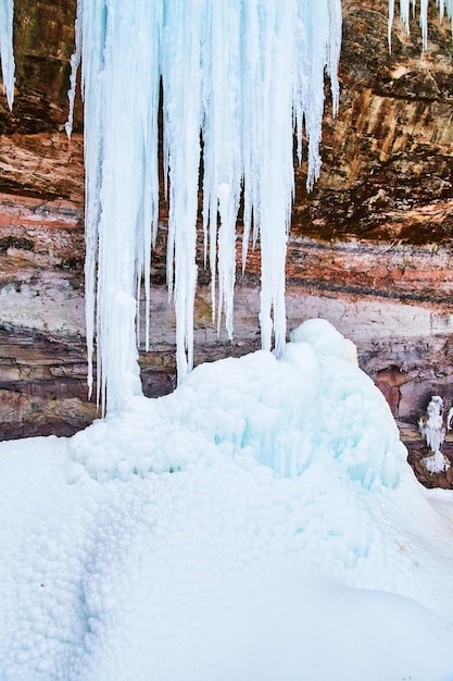 Giant icicles on cliffs forming pile of ice lumps