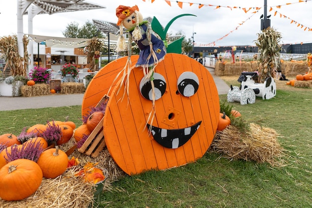 Giant pumpkin on a hay bale with a scarecrow on top and pumpkins around it