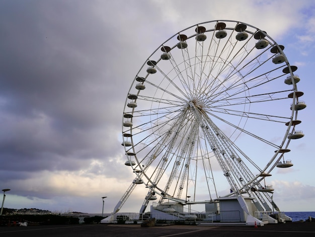 Giant round steel ferris wheel funfair park against cloud sky