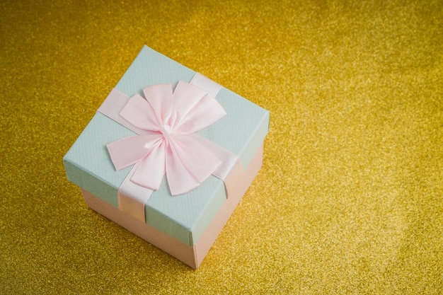 Gift in a beautiful package box with gifts attributes festive mood gift on a gold background