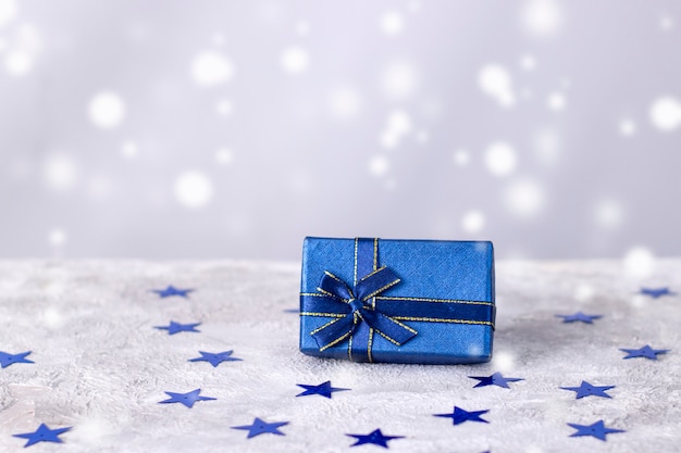 Gift blue box on a light gray background with snow.