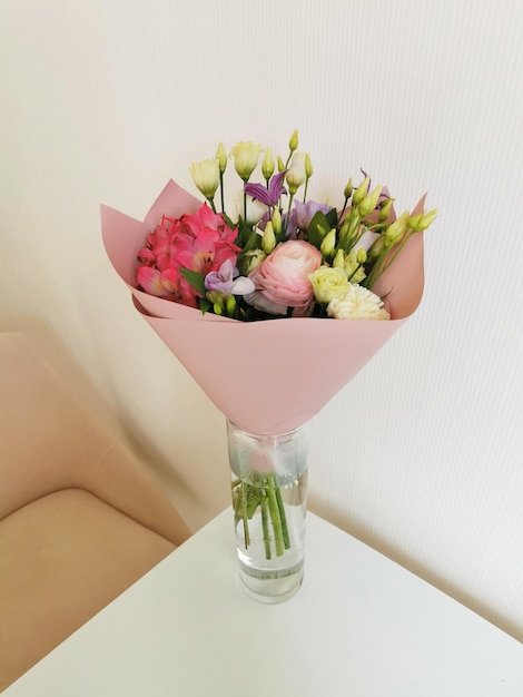 Gift bouquet of eustoma carnation ranunculus alstroemeria on a white table