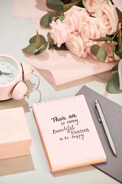 Gift box alarm clock and pink rose flowers on white table top view in flat lay style