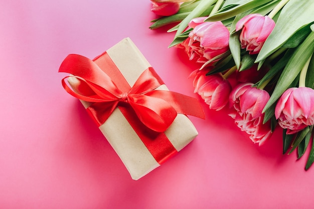 Gift box and bouquet of beautiful tulips on pink