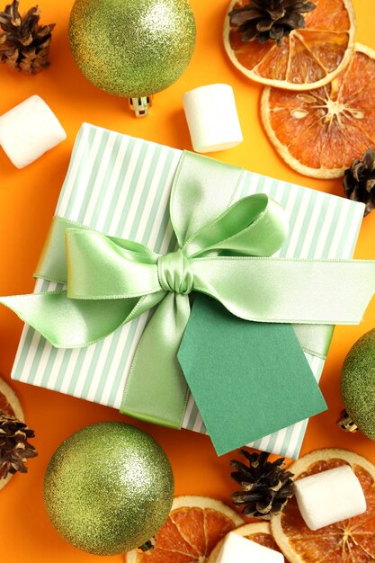 Gift box and Christmas accessories on orange background.