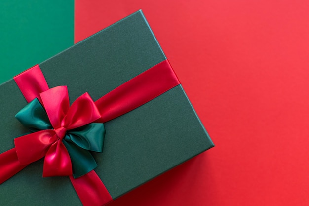 Gift box for Christmas holiday on a green and red background. Place for text