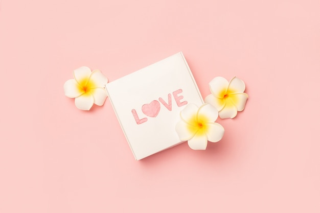 Gift box and flowers on a pastel pink surface