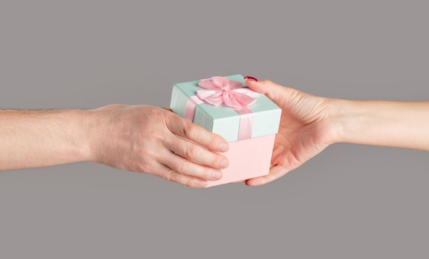 Gift box in hand surprise and holiday concept Man hands holding valentines day gift Male and female hands holding pink gifts box Girl gives a gift to man Woman hands holding gift