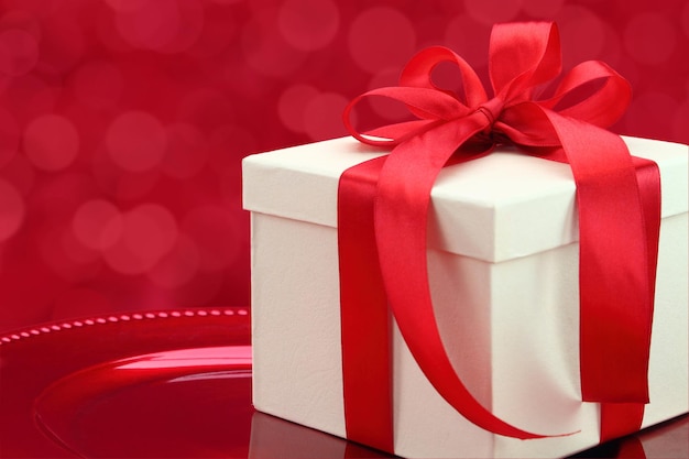 Gift box on a plate with elegant red lights background