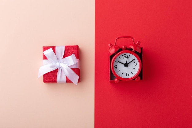 Gift box and red clock on pink and red background