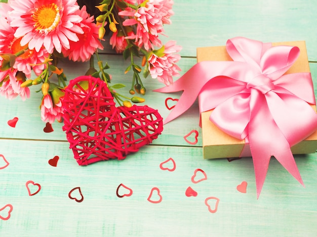 Gift box and red wicker heart on a blue wooden