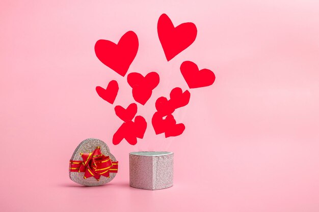 Gift box in the shape of a heart with flying hearts on a pink background. Banner for valentines day or mothers day with copy space.