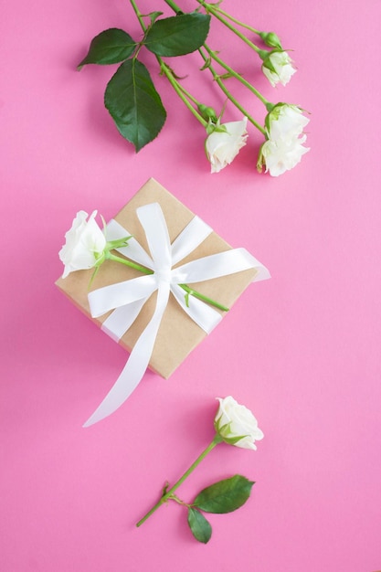 Gift box and white roses on the pink backgroundTop view Location vertical