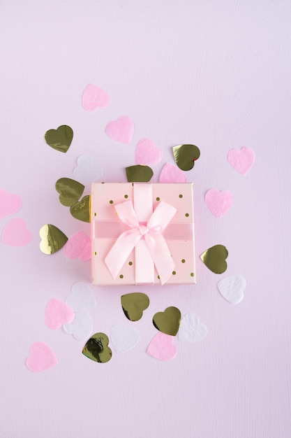 Gift box with bow and hearts decoration on lilac background Valentines Day and Mothers Day Copy