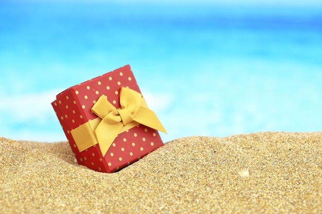 Gift box with bow on the sand